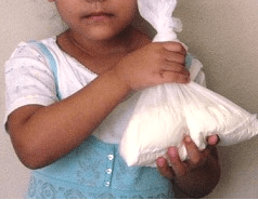 Una niña cubana muestra la cantidad de leche en polvo que le venden por el racionamiento del mes