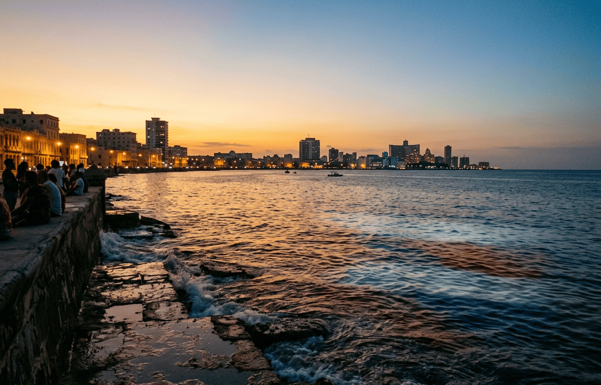 People on a seawall overlooking Havana’s illuminated waterfront at sunset